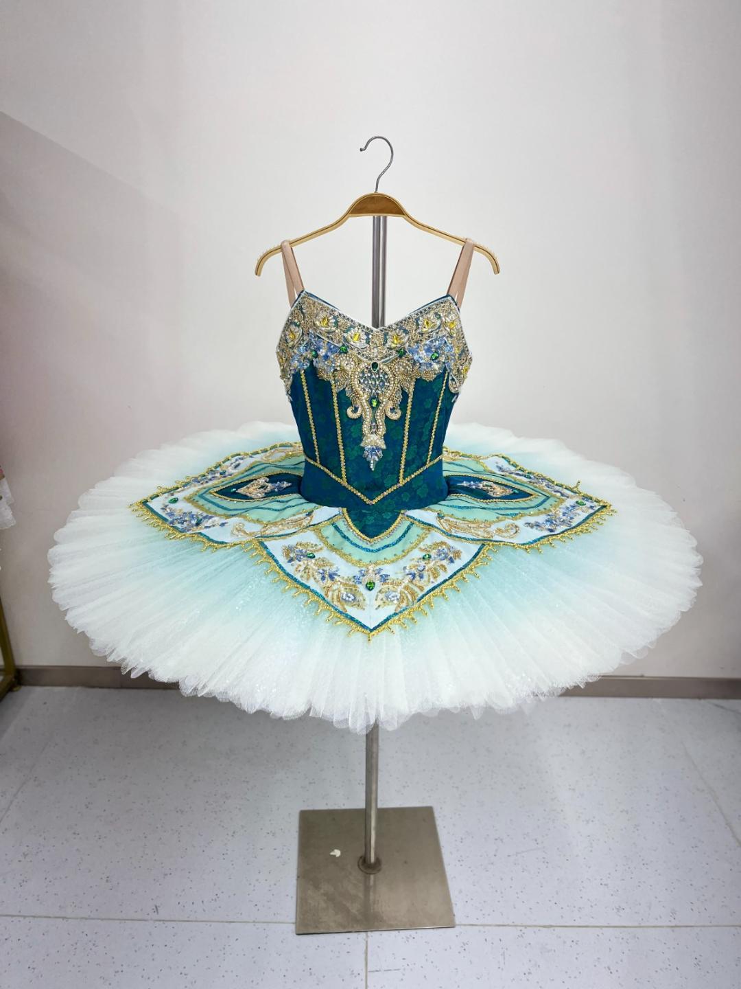 Ballet costume with intricate design on a stand against a plain background